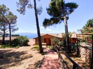 dom z płotem i drzewami przed nim w obiekcie Porto S.Stefano CalaPiccola w mieście Monte Argentario