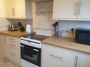 a kitchen with a stove and a microwave at Stylish 3 Bedroom House with Free Parking in Norwich
