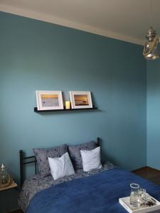 a blue bedroom with a bed with two pictures on the wall at Apartament Mariacka in Nysa