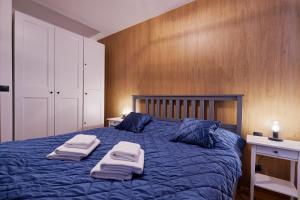 a bedroom with a blue bed with towels on it at RV Apartment Jantár in Vysoke Tatry - Stary Smokovec