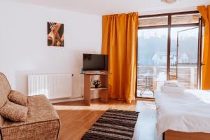 a bedroom with a bed and a tv and a balcony at Pensiunea Bike&Bed in Moieciu de Jos