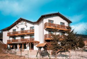 a large white building with wooden balconies at Pensiunea Bike&Bed in Moieciu de Jos