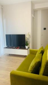 sala de estar con sofá verde y TV de pantalla plana en Proper Central Apartment, en Tirana