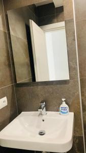 lavabo blanco en el baño con espejo en Proper Central Apartment, en Tirana