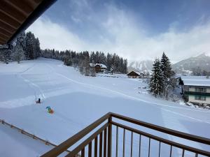 a room with a balcony with a snow covered slope at Moderne Kaminstube in Ramsau am Dachstein