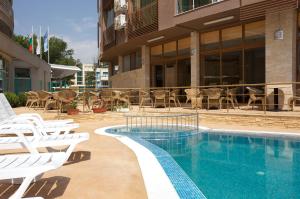 a swimming pool with white lounge chairs next to a building at Briz - Seabreeze Hotel in Sunny Beach