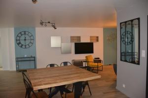 uma sala de jantar com mesa e cadeiras e um relógio em Maison à 200m des plages avec jacuzzi em Trégunc