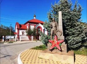 Una statua di un uomo in piedi di fronte a un edificio di Country House Albatros a Praskoveyevka