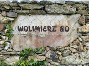 una señal en una valla con la palabra terminada en Wolimierz 80, en Wolimierz