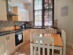 a kitchen with white cabinets and a wooden table at Central Apartments - Spacious 2 Beds in Swindon