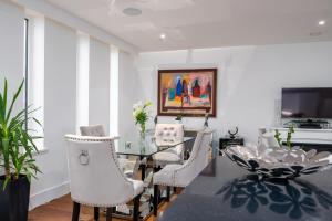 a dining room with a glass table and white chairs at GuestReady - Beautiful Home minutes to City Center in London
