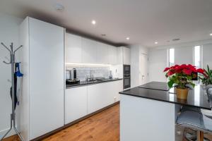 a kitchen with white cabinets and black countertops at GuestReady - Beautiful Home minutes to City Center in London