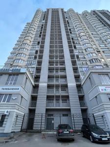 um edifício alto com dois carros estacionados em frente em View Apartments, 22 floor with 2 rooms em Kiev