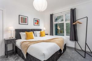 a bedroom with a bed with yellow pillows and a window at Wellington View - Donnini Apartments in Ayr