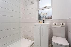 Un baño blanco con inodoro y ventana. en Wellington View - Donnini Apartments, en Ayr
