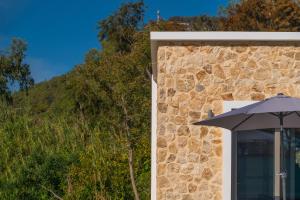 un paraguas sentado al lado de un edificio de piedra en Oliveto A Flumine - Experientia Villa en Pastida