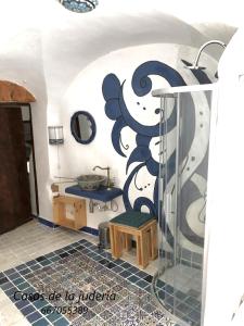 La salle de bains est pourvue d'une douche et d'une fresque murale. dans l'établissement Casas de la Judería, judería nueva, à Cáceres
