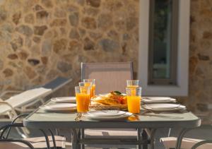 un tavolo con piatto di cibo e bicchieri di succo d'arancia di Oliveto A Flumine - Experientia Villa a Pastida