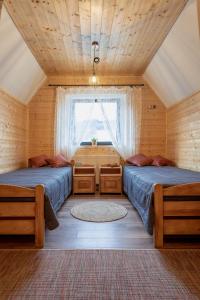 two beds in a room with a window at PUSTELNIA WODZA in Wisła