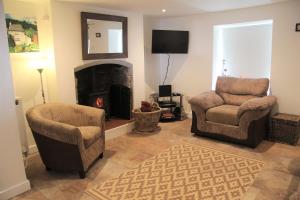 a living room with two chairs and a fireplace at Peacock Cottage in Cinderford