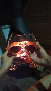 two people holding wine glasses in front of a fireplace at Chalés do Palácio in Campos do Jordão