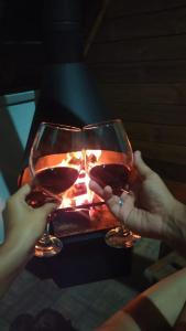 dos personas sosteniendo copas de vino frente a una chimenea en Chalés do Palácio, en Campos do Jordão