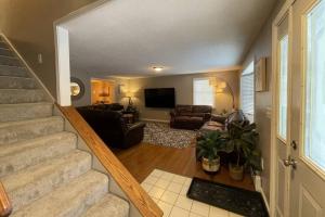 ein Wohnzimmer mit einer Treppe, einem Sofa und einem TV in der Unterkunft Spacious Family Lake & Ski House in Windsor