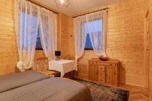 a bedroom with two beds and a table and two windows at PUSTELNIA WODZA in Wisła