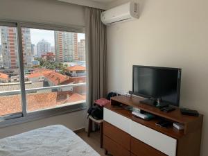 een hotelkamer met een televisie en een groot raam bij Departamento Santos Dumont Punta del Este in Punta del Este