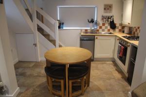 a small kitchen with a table and a staircase at Peacock Cottage in Cinderford