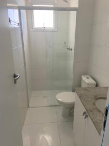 a white bathroom with a shower and a toilet at Apartamento pé na areia in Itanhaém +16 photos