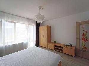 a bedroom with a white bed and a window at Zander Home Apartment in Buşteni