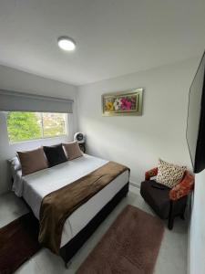 a bedroom with a bed and a window and a chair at Apartaestudio San Gil - Hostal Green in San Gil