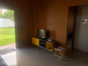 Casa em Ibiraquera próxima a praia do Rosa في إيمبيتوبا: غرفة معيشة مع تلفزيون وكرسي