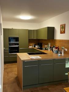 cocina con armarios verdes y encimera de madera en Gästehaus Traunreut - Monteur und Gästezimmer -, en Traunreut