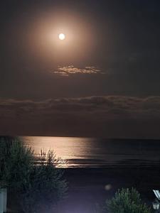 een volle maan die 's nachts boven de oceaan opkomt bij Royal Sea View Design Promenada 3 in Mamaia Nord – Năvodari