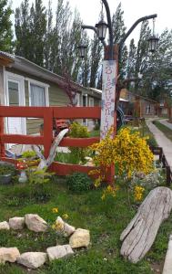 a garden with a red fence and some flowers at Acol in Perito Moreno