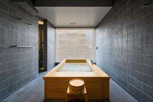 La salle de bains est pourvue d'une baignoire avec un tabouret. dans l'établissement THE MACHIYA HOTEL TAKAYAMA, à Takayama