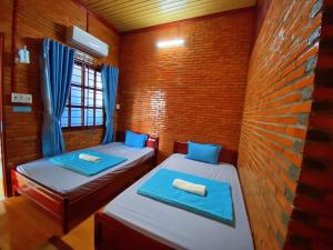 Cette chambre comprend 2 lits et un mur en briques. dans l'établissement Nam Cat Tien Homestay, à Cat Tien