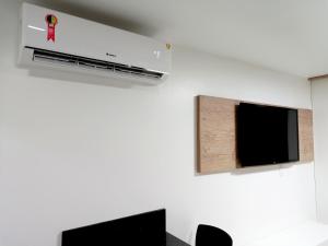 Habitación con aire acondicionado montado en la pared y TV. en Praia dos Carneiros Flat Hotel Apto Completo en Tamandaré