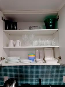 a kitchen shelf with plates and glasses on it at Praia dos Carneiros Flat Hotel Apto Completo in Tamandaré