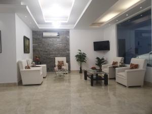 a waiting room with white chairs and a tv at Aristocrat Inn in Dhaka