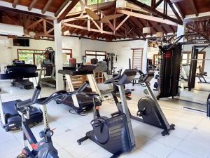 Residência em condom, 1 ou 2 suítes, vista para o mar, Praia do Curral, Ilhabela في إلهابيلا: صالة ألعاب رياضية بها العديد من أجهزة المشي وأجهزة القلب والأوعية الدموية