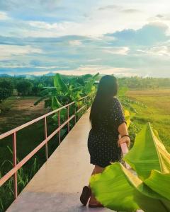 a woman standing on a bridge with a green umbrella at BaanlungchuHomestay&Cafe in Amphoe Mae Taeng