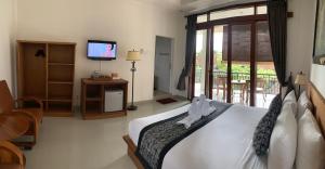 1 dormitorio con 1 cama, TV y balcón en Pondok Serayu, en Ubud