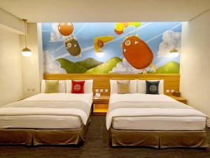 two beds in a room with a painting on the wall at Sun Dialogue Hotel-By Cosmos Creation in Chiayi City