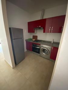 a kitchen with red cabinets and a stainless steel refrigerator at Kariat Cabo - Cabo Negro 32 in Cabo Negro