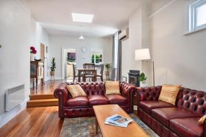 a living room with a leather couch and a table at Warwick St Retreat! 3 Bedroom House With Parking in Hobart