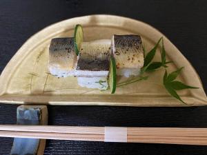 a plate with a sandwich on a table with chopsticks at Guest House Mitsuka in Shishikui