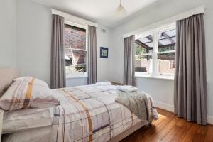 a bedroom with a bed and two windows at Warwick St Retreat! 3 Bedroom House With Parking in Hobart